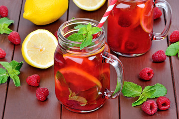Raspberries lemonade in a jars on a wooden table