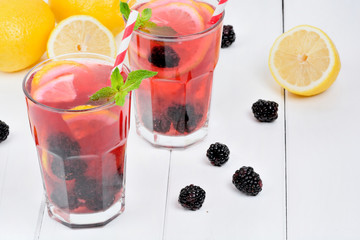 Blackberries lemonade in a glasses on a white wooden background