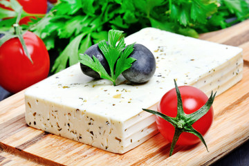 Herbs cheese with olive and cherry tomatoes on a cutting board