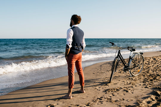 Well dressed man with his bike standing on a beach