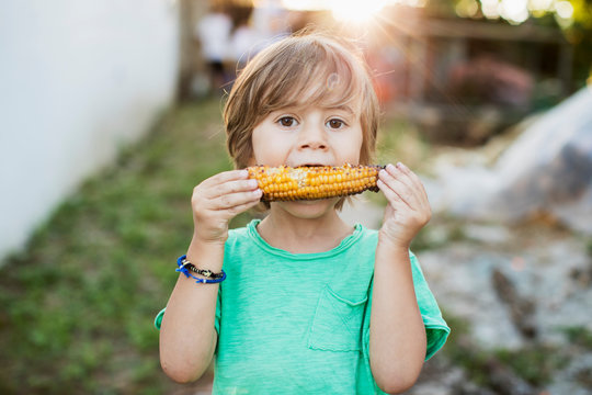 3 year old boy eating baked corn