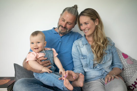 Happy family of three sitting on a bench at home