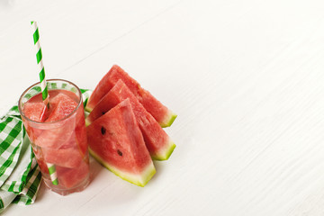 Watermelon smoothie in a glass, on a white table, with a green napkin. Copy space.