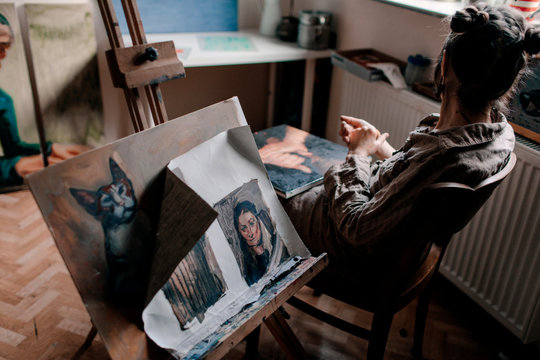 Female artist sitting in her studio with paintings