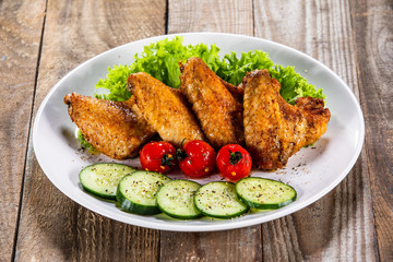 Grilled chicken wings with vegetables on white plate
