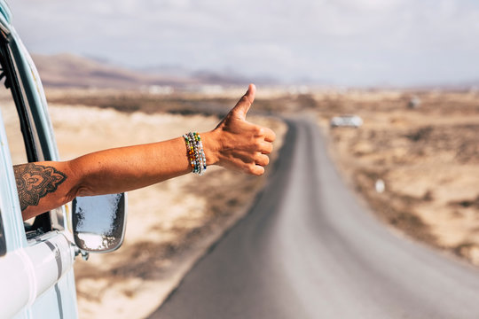 Traveler sitting in van, showing thumb up out of the window