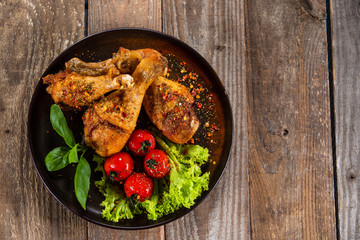 Fried chicken drumsticks with vegetables on wooden table