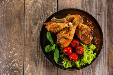 Fried chicken drumsticks with vegetables on wooden table