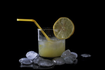 Glass, ice cubes with orange juice and slice lemon isolated on black background