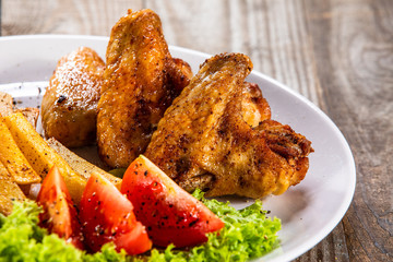 Grilled chicken wings, chips and vegetables