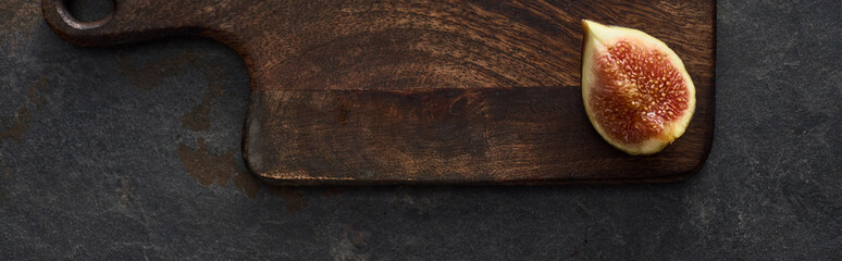 panoramic shot of ripe fig on wooden cutting board on stone background