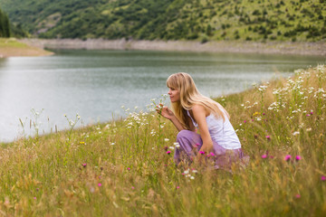 Woman smelling flowers while spending time in the beautiful nature.