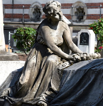 Trauernde Frau auf einem Grab sitzend