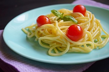 Delicious spaghetti with herbs and tomatoes on a black background.