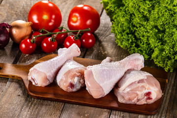 Raw chicken drumsticks on wooden background