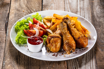 Grilled chicken drumsticks with baked potatoes and vegetables