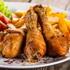 Grilled chicken drumsticks with baked potatoes and vegetables