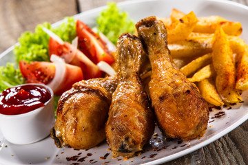 Grilled chicken drumsticks with baked potatoes and vegetables