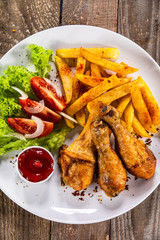 Grilled chicken drumsticks with baked potatoes and vegetables