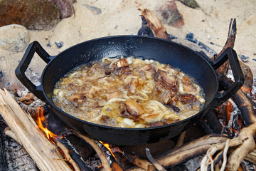 Pieces of lamb with onion are fried in boiling oil on the fire. As a stage in the preparation of traditional pilaf.