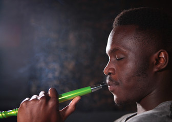 Fototapeta premium Portrait of an African American on a black background. A man smokes a hookah.