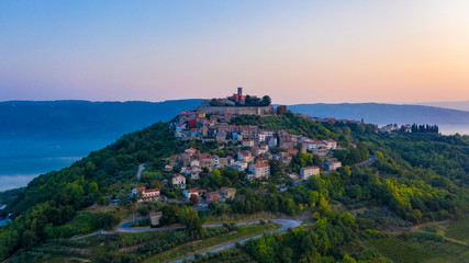 Naklejka premium The ancient city of Motovun is located on the top of the mountain. The city is surrounded by a fortress wall. The background image are mountains and fog at the foot of the mountains. Istria, Croatia.