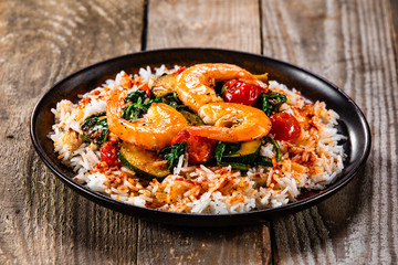 Shrimps with white rice and vegetables on wooden table