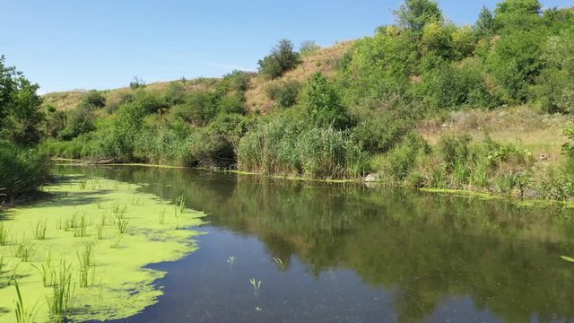 Wildlife of Russia: a small river among hills and meadows on a summer day