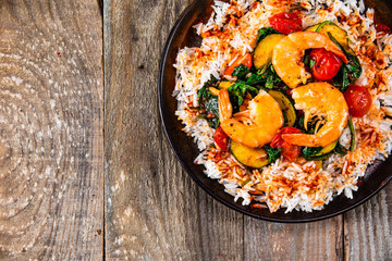 Shrimps with white rice and vegetables on wooden table