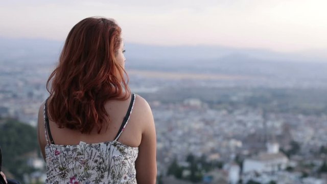 young redhead woman contemplating the city at sunset