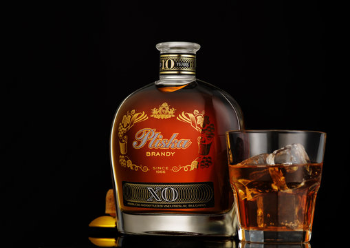 Bottle of Pliska - the Bulgarian grape brandy with a glass on a black background.