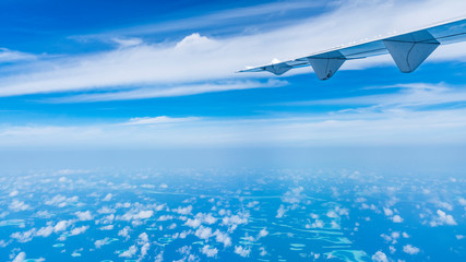 Aircraft wing flying over the blue clouds.