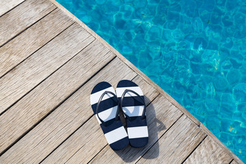 Flip flops  at the side of swimming pool, summer travel concept. - obrazy, fototapety, plakaty
