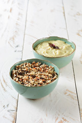 Two beautiful blue porcelain bowls on a white wooden table, one served with rice and whole grains, the other with smashed potatoes