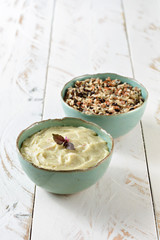Two beautiful blue porcelain bowls on a white wooden table, one served with rice and whole grains, the other with smashed potatoes
