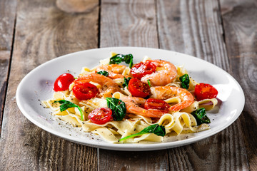 Shrimps with pasta tagliatelle with spinach and tomatoes