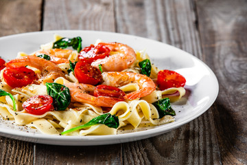 Shrimps with pasta tagliatelle with spinach and tomatoes