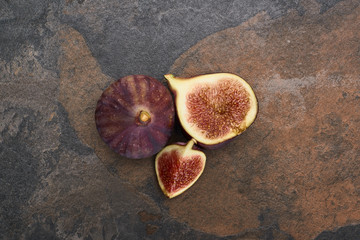 top view of ripe whole and cut figs on stone background