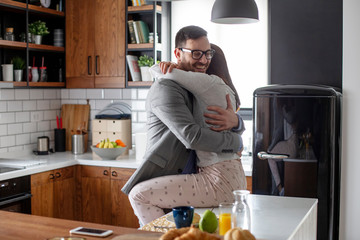 Couple in love hugging at the morning before he is going to the office in the kitchen