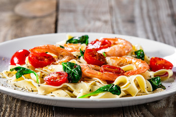 Shrimps with pasta tagliatelle with spinach and tomatoes