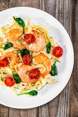 Shrimps with pasta tagliatelle with spinach and tomatoes