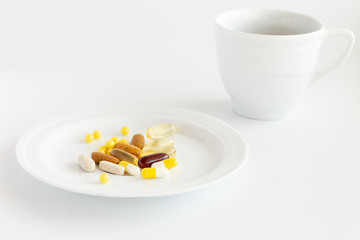 Fototapeta na wymiar pills and vitamins on the white plate with a tea cup on a white background