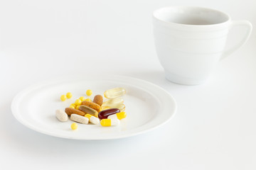 pills and vitamins on the white plate with a tea cup on a white background