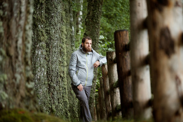 A man stands on a beautiful alley of moss-covered trees and an old wooden fence
