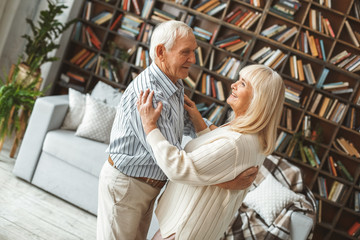 Senior couple together at home retirement concept dancing ballroom dance hugging