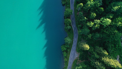 Aerial view of road between Klöntalersee lake and green trees. Glarus, Switzerland.