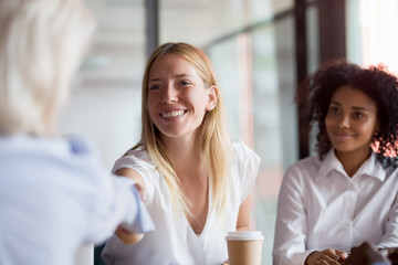Smiling female employee handshake colleague at company meeting