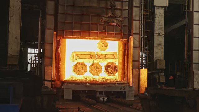 Work tick-borne crane at an engineering plant. The crane lifts the hot steel billets to move into the forging press.