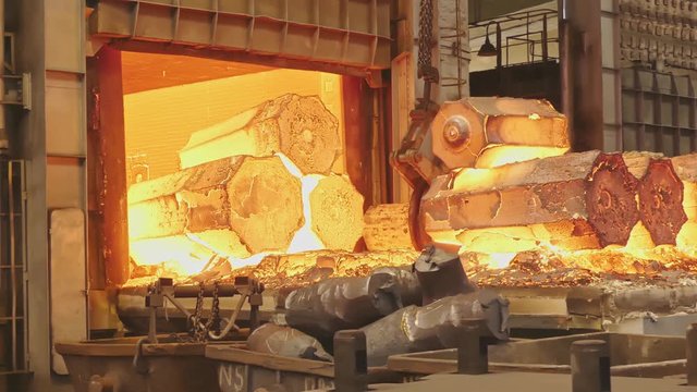 Work tick-borne crane at an engineering plant. The crane lifts the hot steel billets to move into the forging press.