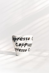 Single ceramic coffee cup, hand written words, with ethereal light and shadows